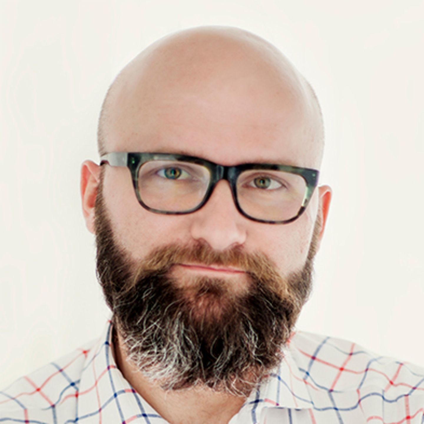 Dr. hab. Tomasz Piekot, oblečený v kostkované košili, se opírá o zeď se zkříženýma rukama.