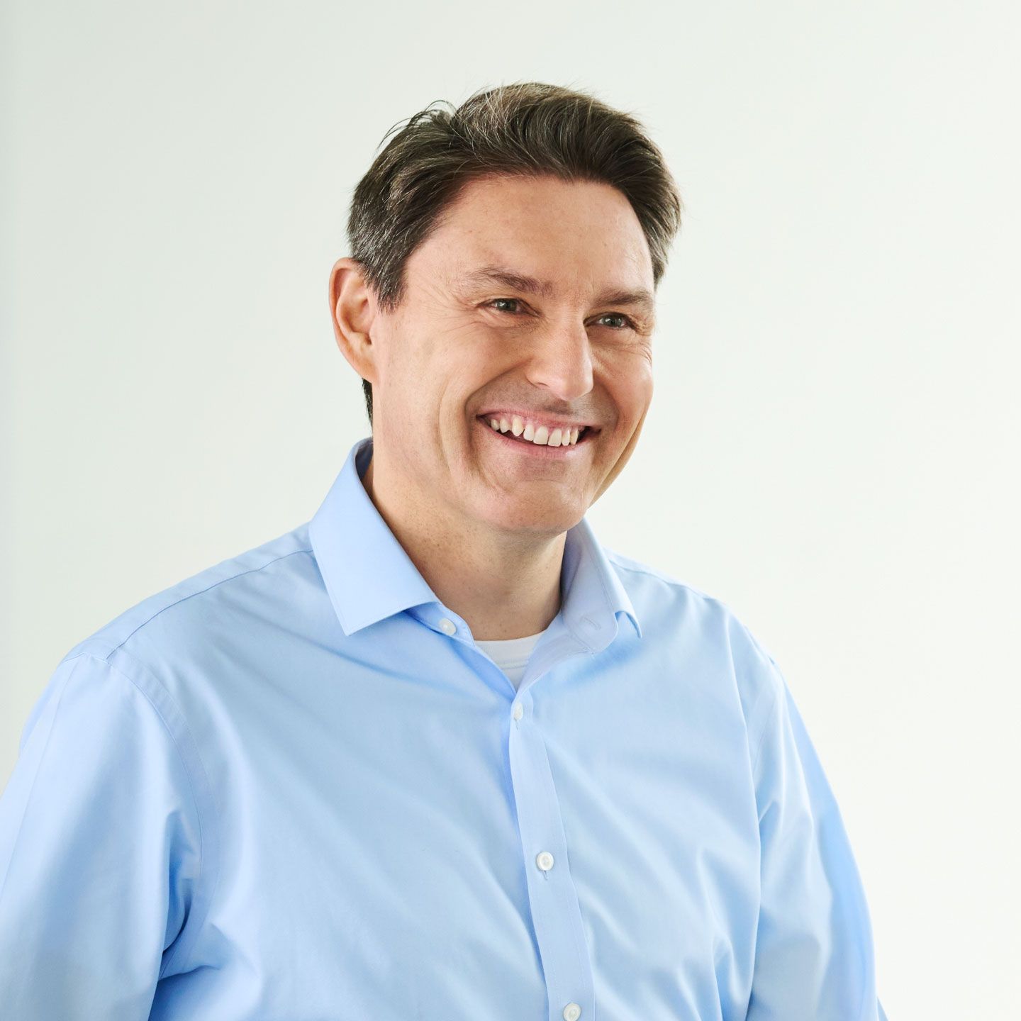 Stephan Ohlmeyer, muškarac u svijetloplavoj košulji, stoji nasmijan u svijetloj prostoriji