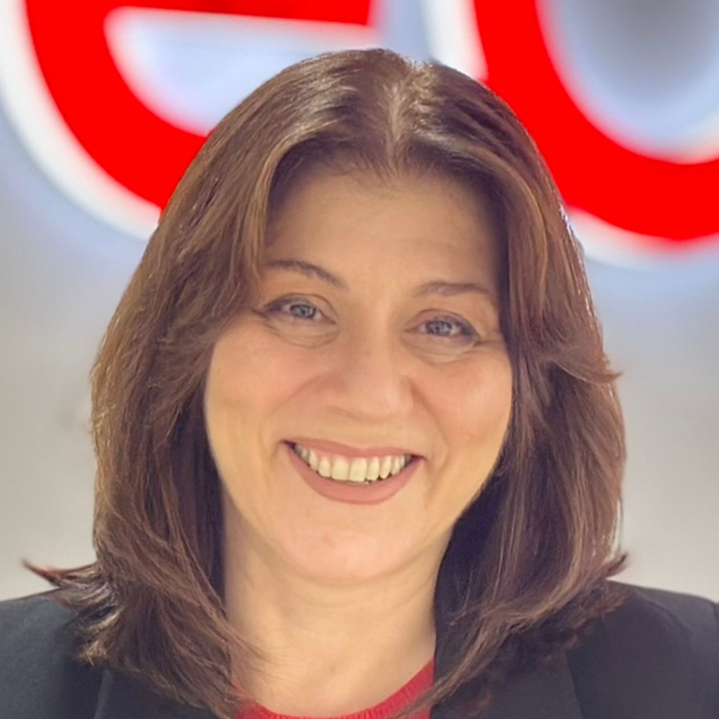 Belén Barreiro, agent kontaktního centra společnosti EOS ve Španělsku, se opírá o pult v černém saku před jasným logem EOS.