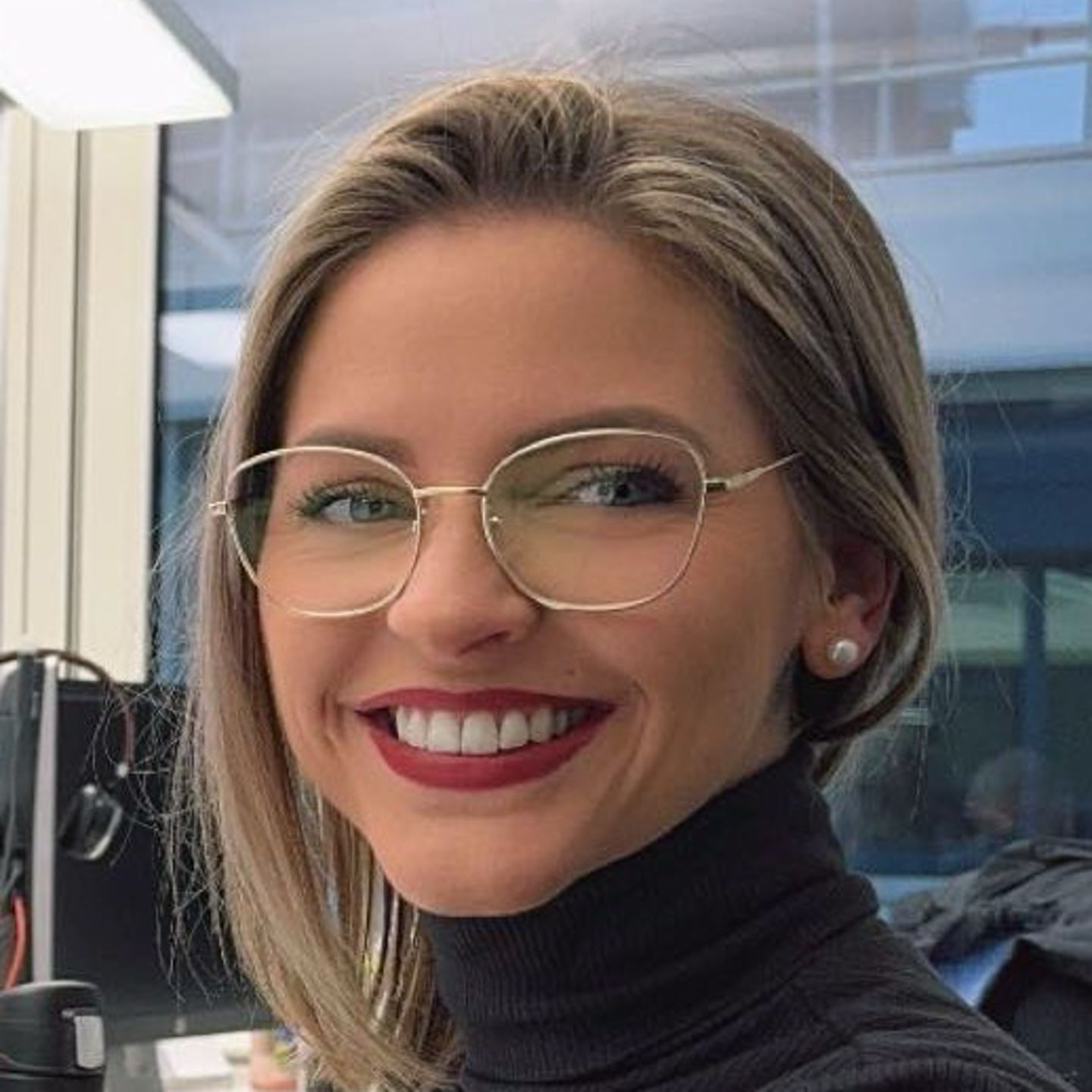 Genny Bollingerová, specialistka na restrukturalizaci dluhu ze společnosti EOS ve Švýcarsku, sedí u svého stolu v šedém roláku a usmívá se do kamery.