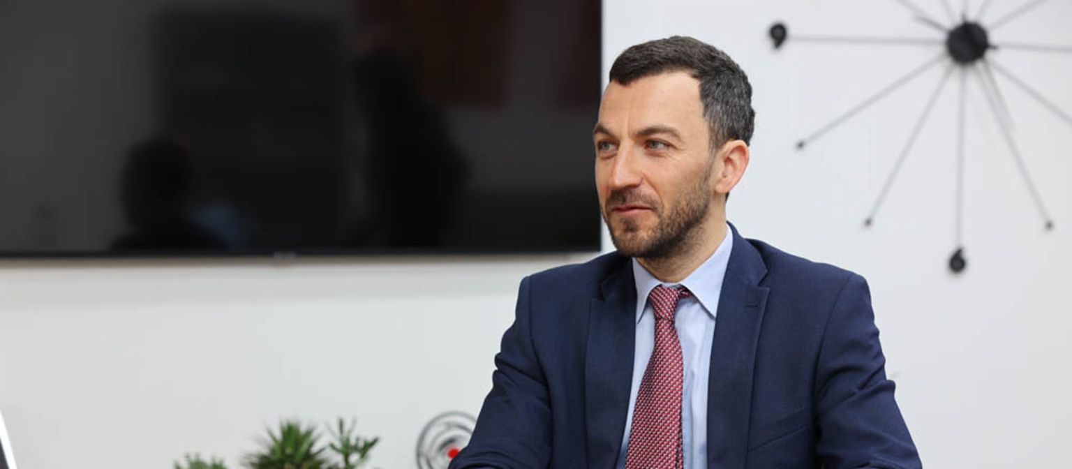 Vladislav Hadjidinev CEO of UNIBANKA is sitting at an office desk with a red folder in front of him