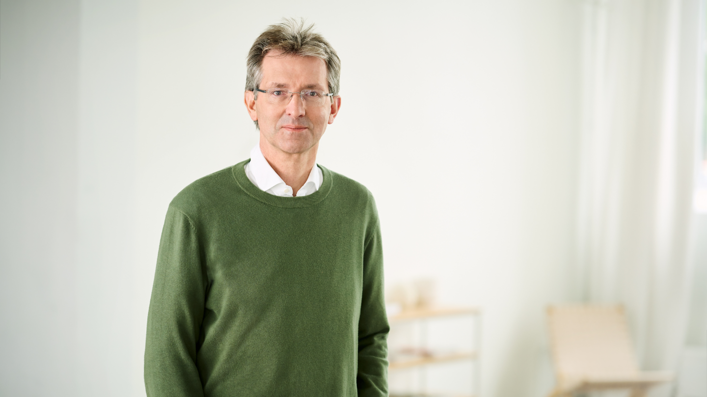 Justus Hecking-Veltman, CFO, standing in a forest green sweater and white shirt in a bright room.